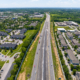 A drone photo of I-71. The highway has some cars on it. It cuts the picture in half. There are houses on either side of the highway.
